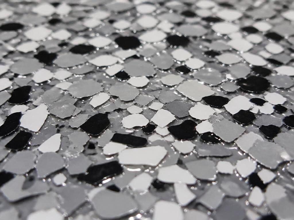 Close-up of gray and black decorative epoxy flakes in a clear topcoat