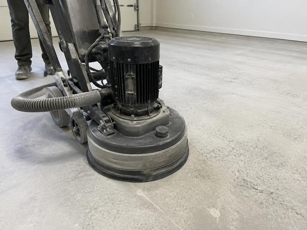 Diamond grinder preparing a bare concrete garage slab before coating